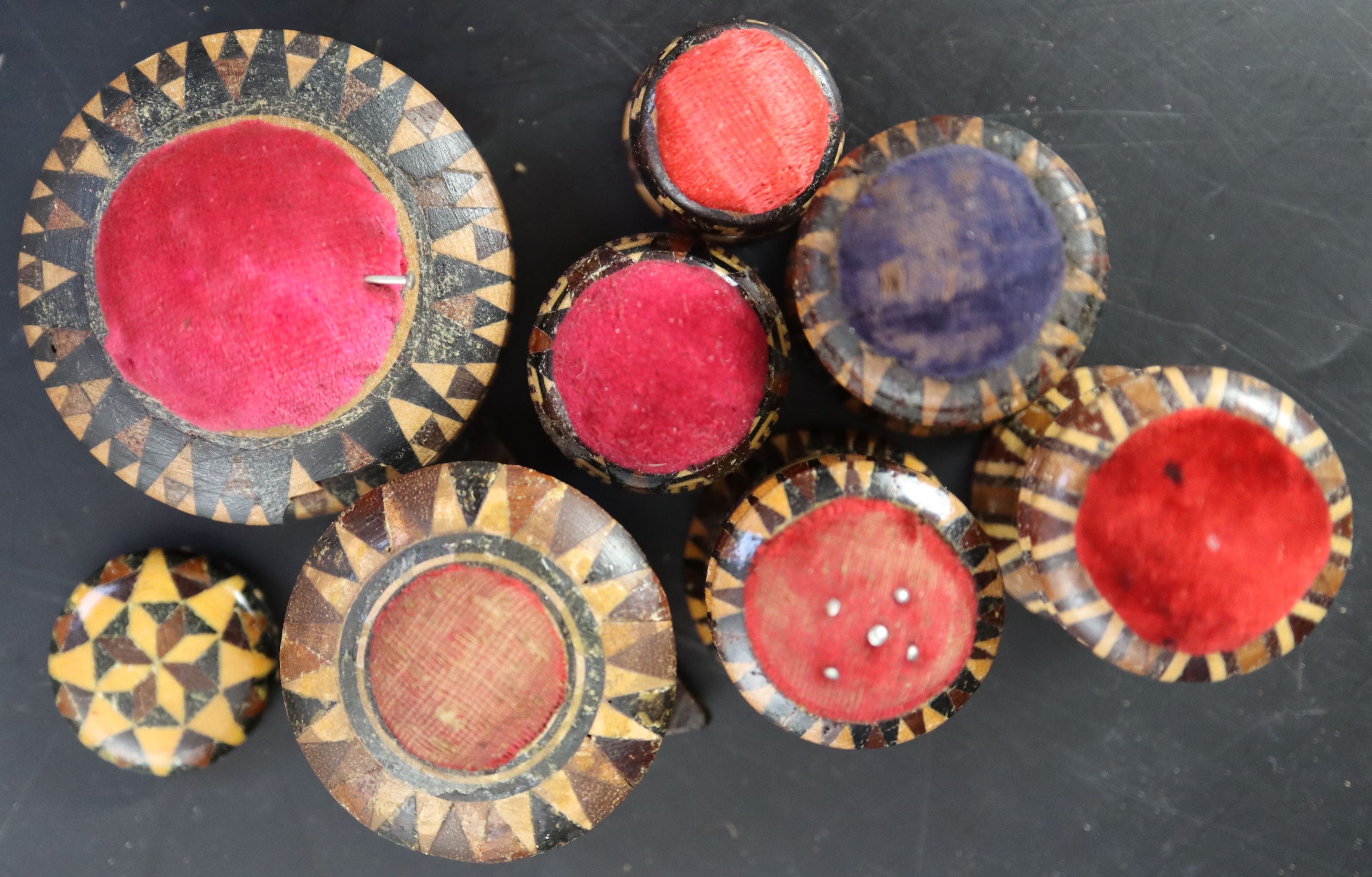 Seven assorted Victorian Tunbridgeware pin cushions and a small spool